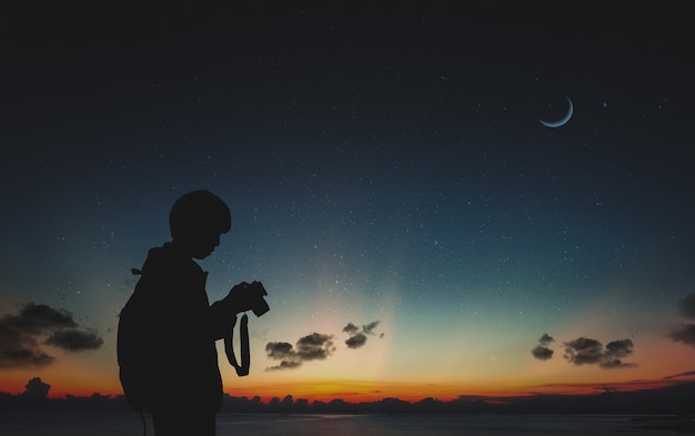 Schattenbild des Fotografen stehend in der Natur mit Mond und nächtlichem Himmel.