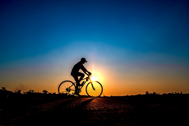 Foto schattenbild des radfahrers im sonnenunterganghintergrund.