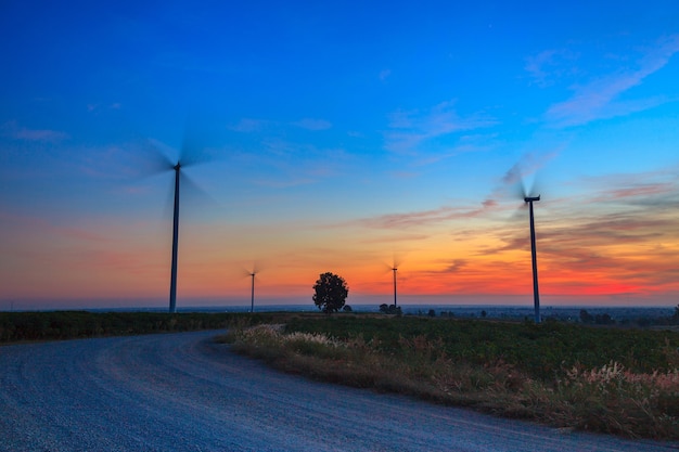 Schattenbild des Windturbinenstromgeneratorbauernhofs bei Sonnenuntergang