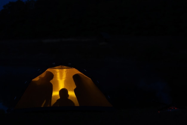 Schattenbild einer Familie in einem Zelt. Camping mit der Familie in der wilden Natur