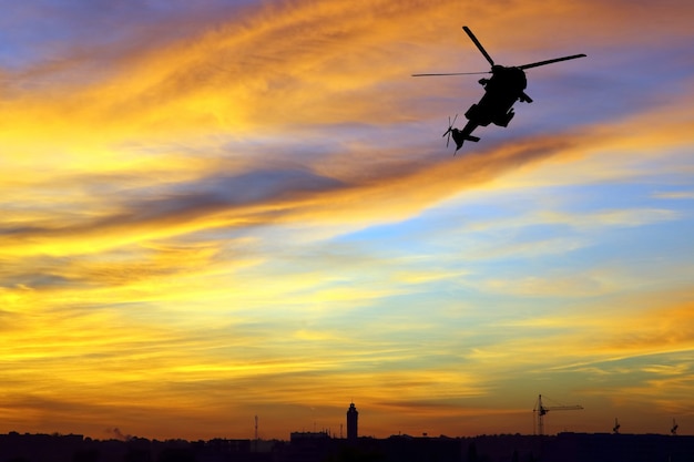 Schattenbild eines fliegenden Hubschraubers gegen den hellen Abendhimmel