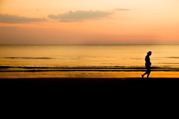 Schattenbild eines Mannes, der am Strand bei Sonnenuntergang joggt