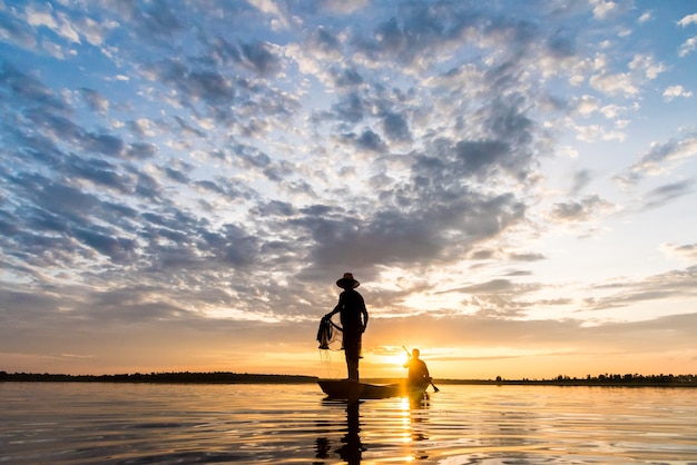 Schattenbild von den Fischern, die Netzfischen in der Sonnenuntergangzeit bei Wanon Niwat Sakon Nakhon werfen