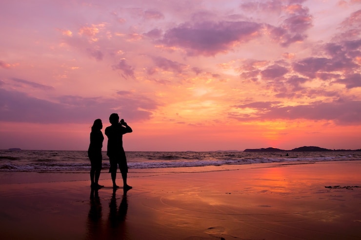 Foto schattenbild von den romantischen paaren, die auf dem strand bei sonnenuntergang stehen