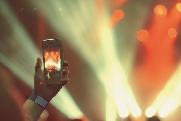 Schattenbild von Händen mit einem Smartphone an einem Konzert
