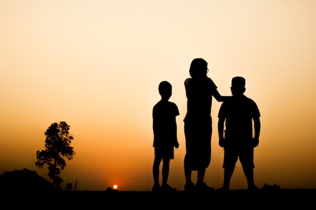 Schattenbild von Kindern mit schönem Sonnenunterganghintergrund.