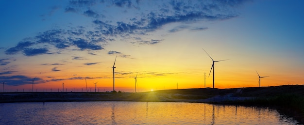 Schattenbilder des Kraftwerks der Windgeneratoren auf dem See bei Sonnenuntergang