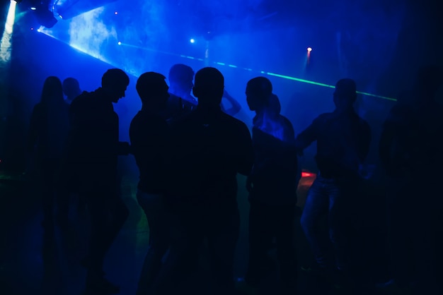 Schattenbilder von den Leuten, die in Nachtklub auf Tanzfläche an der Partei tanzen