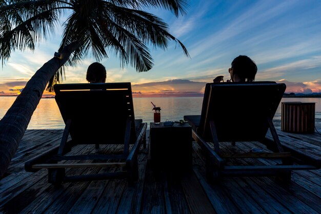 Schattenbildfrau sitzen auf dem Strandstuhltrinkenden Cocktail, der s aufpasst