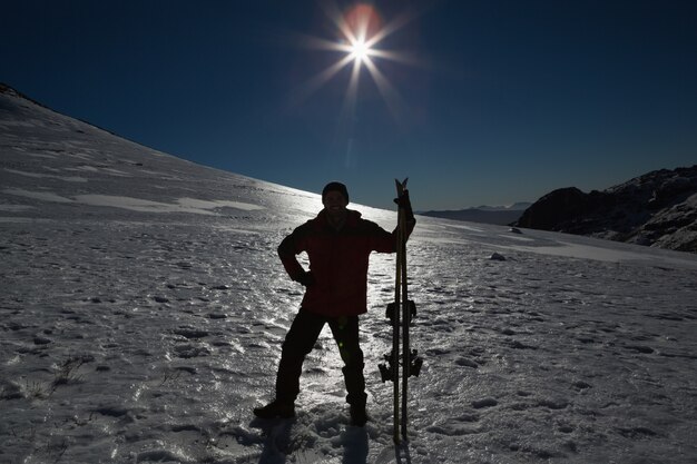 Schattenbildmann mit dem Skibrett, das auf Schnee steht