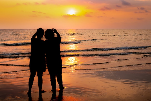 Schattenbildpaare auf dem strandsonnenunterganghintergrund