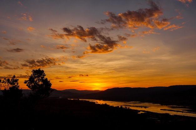 Schattenbildsonnenaufganghimmel über Fluss und Berg