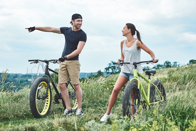 Schau es dir an, ein Mann und eine Frau lachen und laufen in der Nähe ihrer Fatbikes