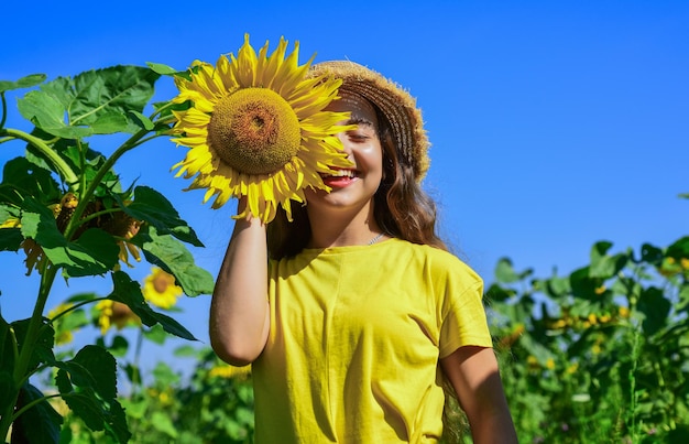 Schau es dir an. gelbe blume der sonnenblume. glückliche Kindheit. schönes Mädchen tragen Stroh Sommerhut im Feld. hübsches Kind mit Blume. Schönheit der Sommernatur. kleines Mädchen im Sonnenblumenfeld.