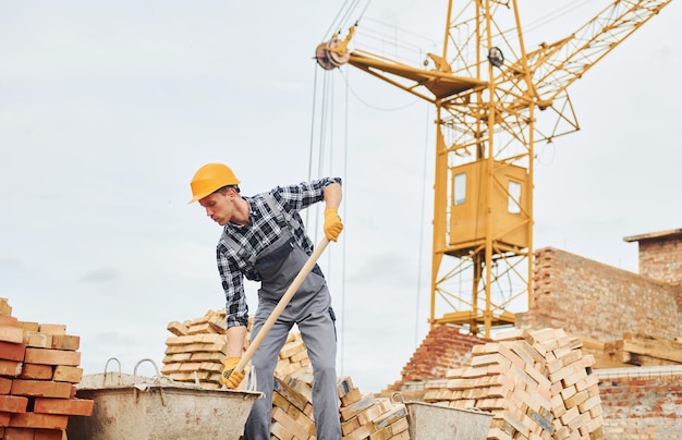 Schaufel mit Holzhalter verwenden Bauarbeiter in Uniform und Sicherheitsausrüstung haben Arbeit am Bau