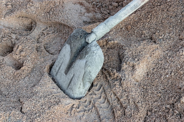 Schaufelschaufel in Beton in einem Sandhaufen verschmiert, um Beton zu machen.