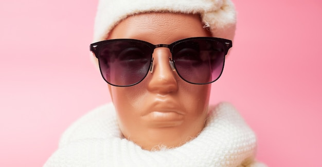 Schaufensterpuppe mit Brille und Schal, Ermäßigungen auf Winterkleidung und Accessoires, auf rosa Hintergrund