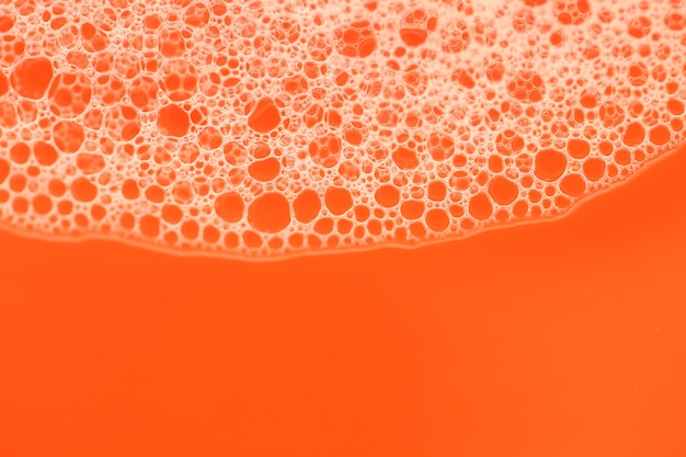 Schaumnahaufnahmeblasen auf einem hellen orange Hintergrund. Orange Seifenschaum