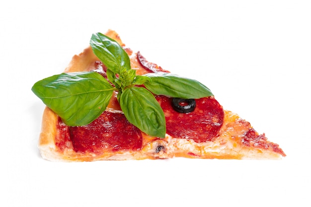 Scheibe der geschmackvollen Pizza mit dem Gemüse und Basilikum getrennt auf Weiß