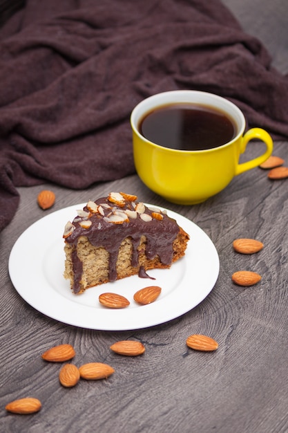 Scheibe des selbst gemachten Bananenbrotes mit Schokolade, Mandel und gelbem Tasse Kaffee auf Holz