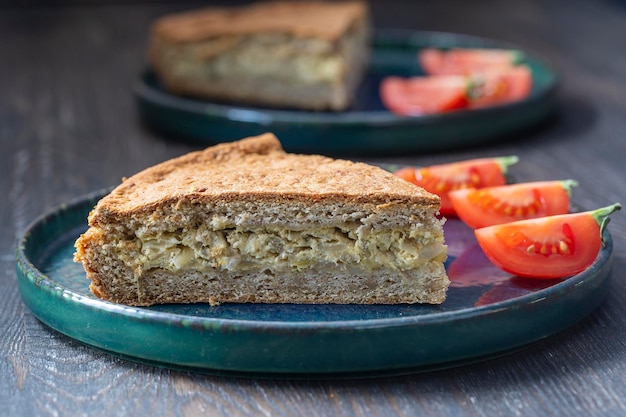 Scheibe hausgemachter Zwiebelquiche, eine gebackene Sahne-Eier-Torte mit Käse und grünen Kräutern