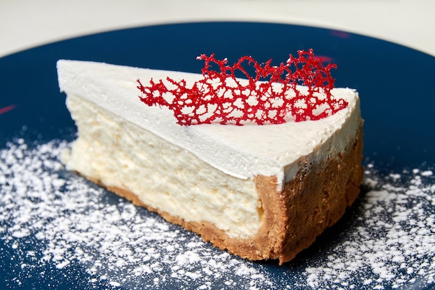 Scheibe Käsekuchen auf blauem Teller mit Karamelldekor