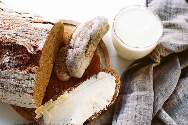 Scheibe rustikales hausgemachtes Roggenmehlbrot mit Butter und Glas Milch