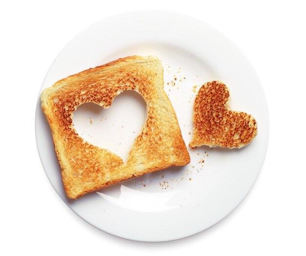 Scheibe Toastbrot mit ausgeschnittener Herzform in einem Teller auf weißem Hintergrund