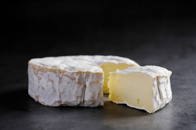 Scheibe Ziegen-Camembert-Käse am dunklen Tisch