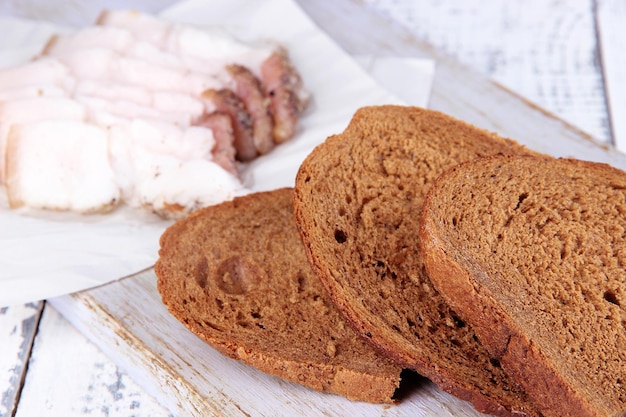 Scheiben Brot und Schmalz auf Schneidebrett auf Holzhintergrund