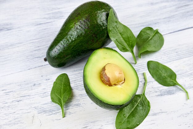 Scheiben der Avocado auf weißem Hintergrund. Ganze und halbe mit Blättern.