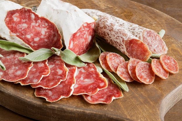 Scheiben der französischen Käse-getrockneten Salami mit Gewürzen auf hölzernem Hintergrund