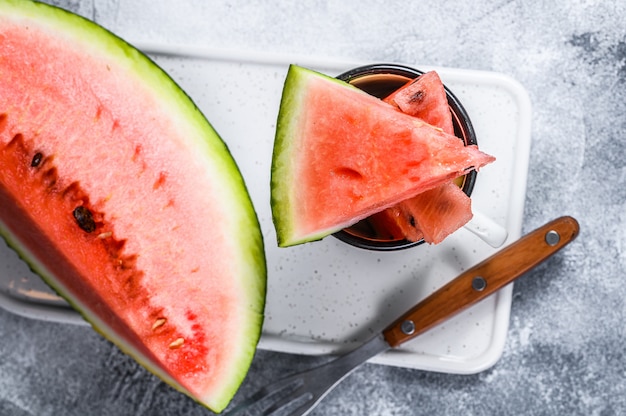 Scheiben der reifen Wassermelone auf einem weißen Schneidebrett.