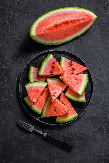 Scheiben der reifen Wassermelone in einer Platte auf Dunkelheit