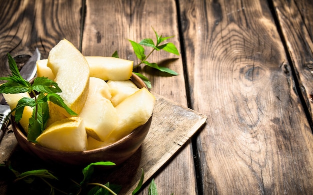 Scheiben der süßen Melone mit Minzzweigen. Auf einem Holztisch.