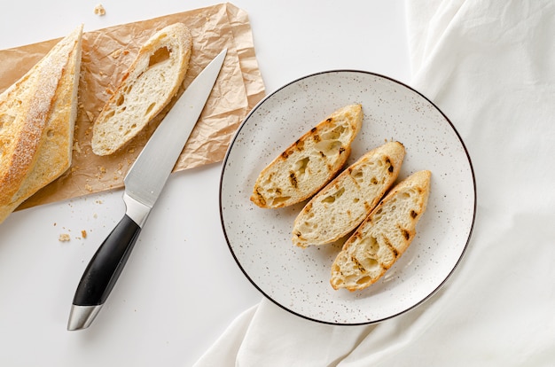 Scheiben des gerösteten französischen Stangenbrots auf weißer Platte zum Frühstück