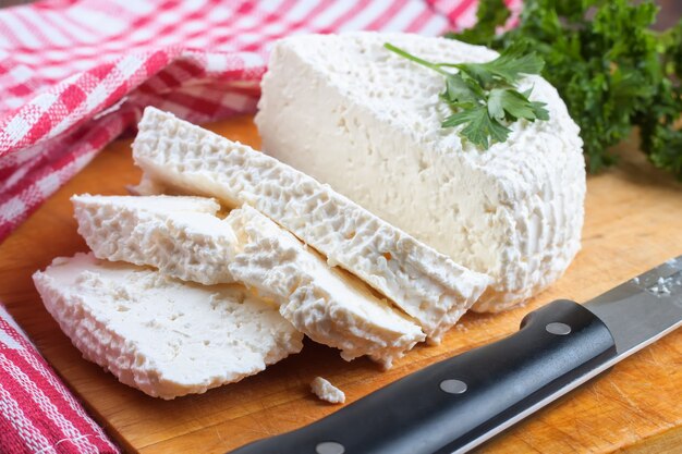 Scheiben frischer Hüttenkäse auf Holzschneidebrett