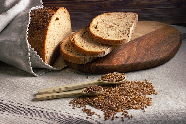 Scheiben frisches hausgemachtes Brot auf Holzbrett mit Vollkorn und Holzlöffeln