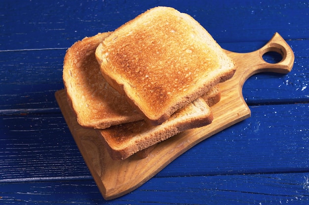 Scheiben geröstetes Brot auf blauem Holztisch hautnah