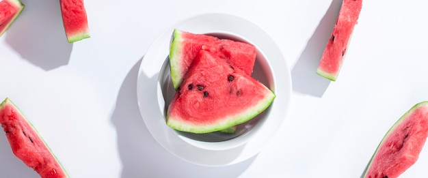 Scheiben reife Wassermelone auf einem Teller auf weißem Hintergrund. Ansicht von oben, flach. Banner.