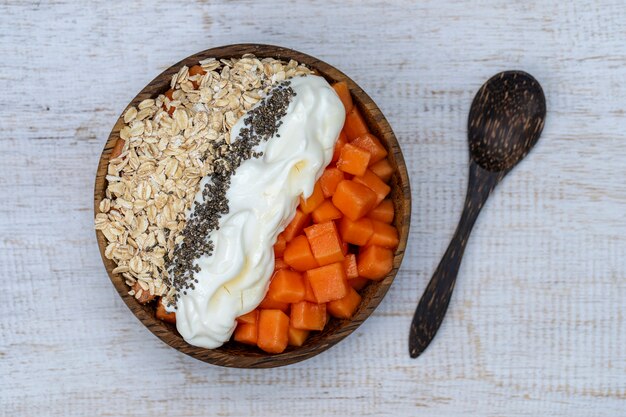 Scheiben reifer süßer Papaya-Früchte mit Haferflocken, Chiasamen und weißem Joghurt