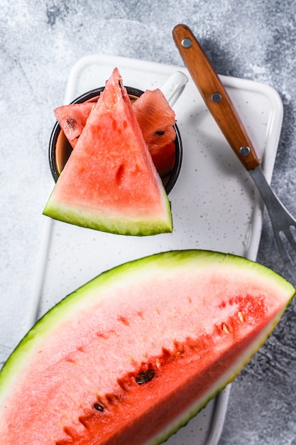 Scheiben reifer Wassermelone auf einem weißen Schneidebrett.