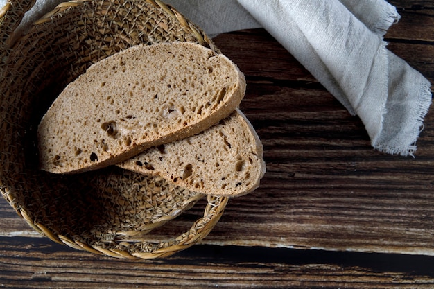 Scheiben rustikales Brot in Korbschale auf einem Holztisch