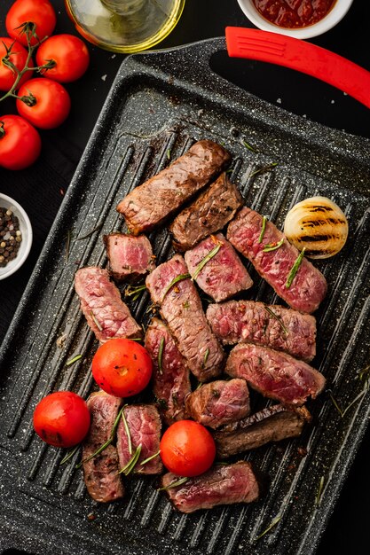 Scheiben saftiges Steak mit Kirschtomaten auf Grillpfanne.