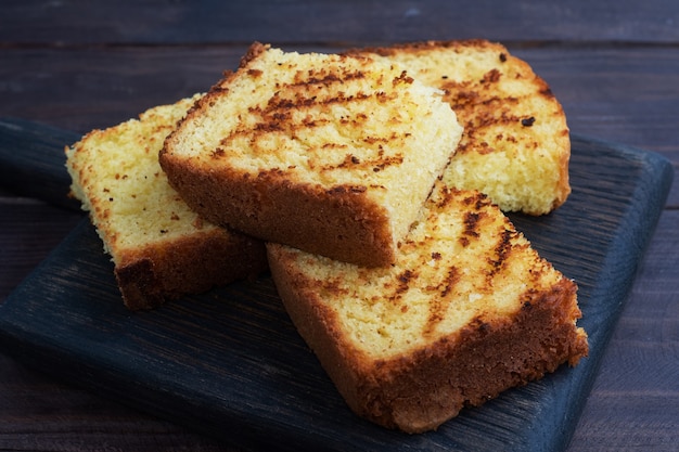 Scheiben Toastweizenbrot auf einem dunklen Holztisch.