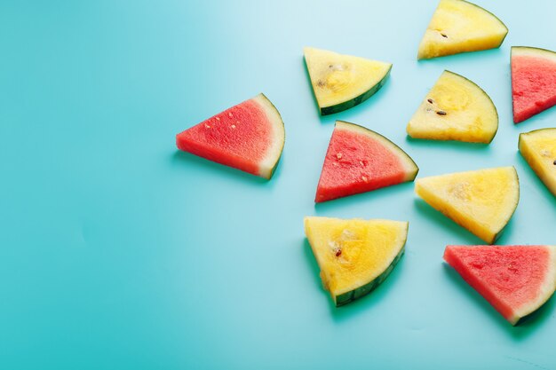 Scheiben von frischen Stücken gelber und roter Wassermelone auf einem Blau. Freier Platz.