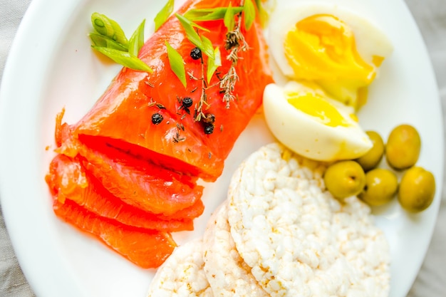 Scheiben von gesalzenem rohem Fischfilet mit Ei und Reiskuchen. Selektiver Fokus. Paleo-Diät-Mahlzeit. Gesundes Konzept für proteinreiche und kohlenhydratarme Produkte.