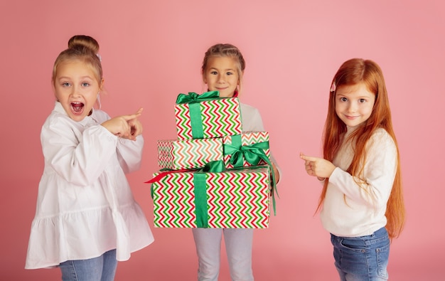 Schenken und Beschenken an den Weihnachtsfeiertagen. Gruppe glücklicher lächelnder Kinder, die Spaß haben