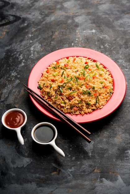 Schezwan Fried Rice Masala é uma comida indo-chinesa popular servida em um prato ou tigela com pauzinhos. foco seletivo