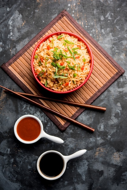 Foto schezwan fried rice masala é uma comida indo-chinesa popular servida em um prato ou tigela com pauzinhos. foco seletivo